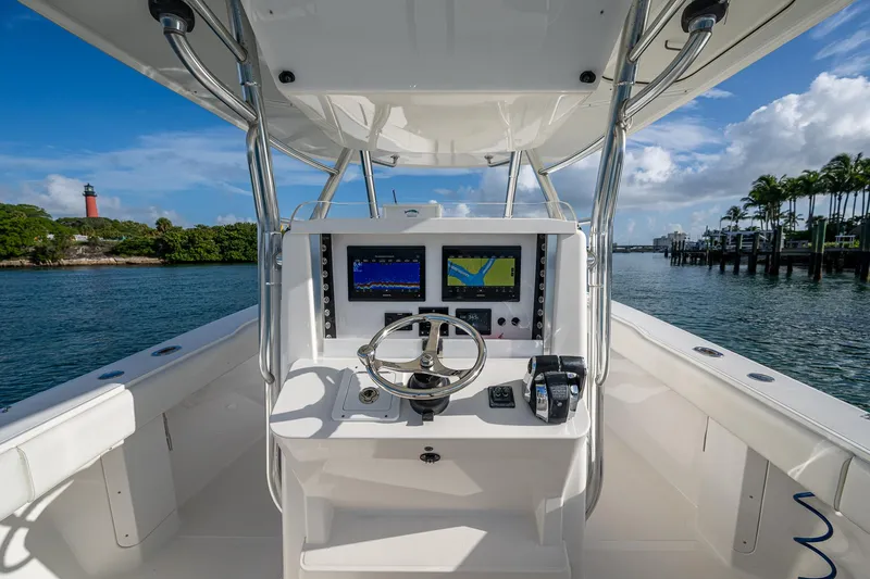 Poliseas Yacht Photos Pics 2006 Bahama 31 boat helm with navigation screens, steering wheel, and scenic waterfront view.