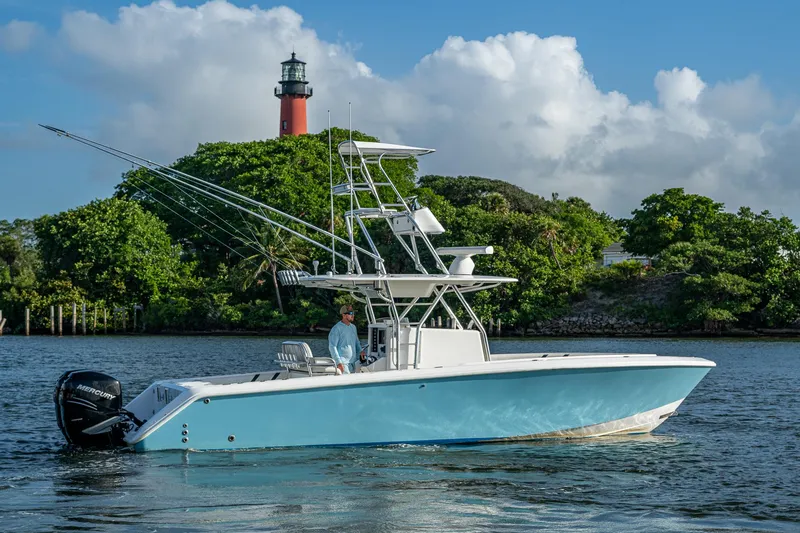 Poliseas Yacht Photos Pics 2006 Bahama 31 boat on water near lighthouse, lush greenery in background.