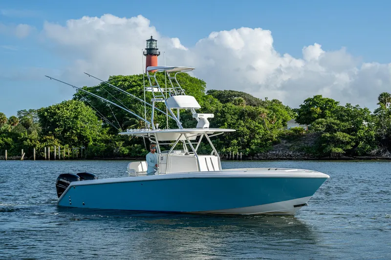 Poliseas Yacht Photos Pics 2006 Bahama 31 boat cruising near a lighthouse, surrounded by lush greenery.