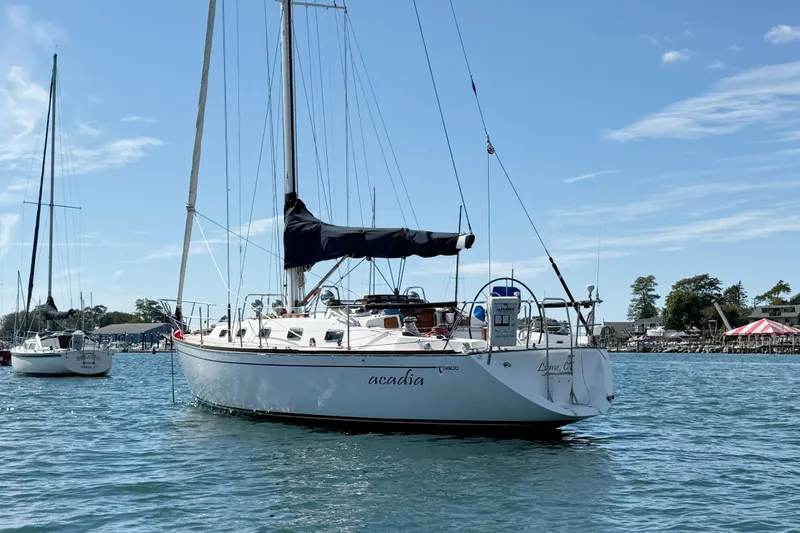 Acadia Yacht Photos Pics Sailboat Tartan 3800, 1997 model, anchored in a scenic harbor under a clear blue sky.