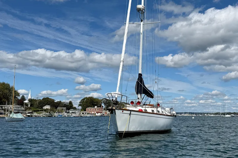 Acadia Yacht Photos Pics Sailboat Tartan 3800 (1997) anchored in scenic harbor under blue sky and clouds.