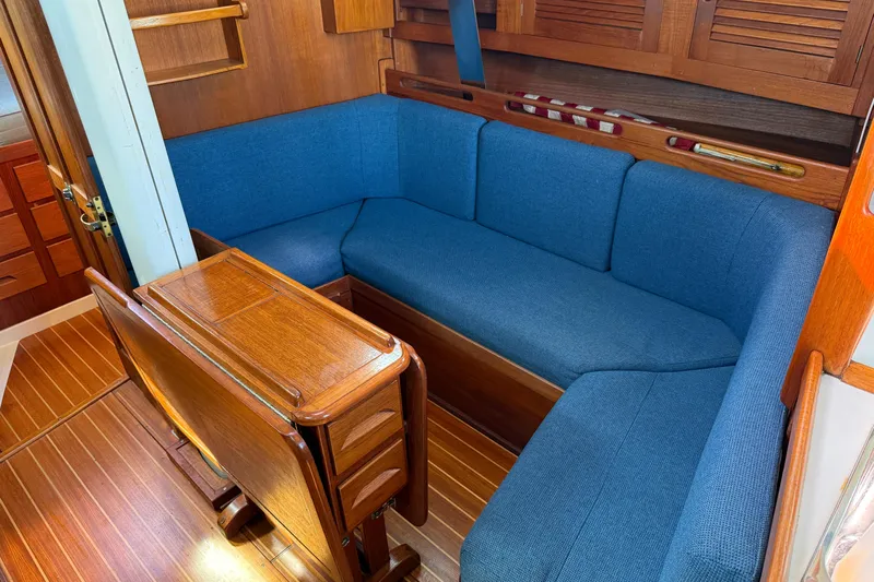 Acadia Yacht Photos Pics Cozy 1997 Tartan 3800 yacht interior with blue cushioned seating and wooden table.