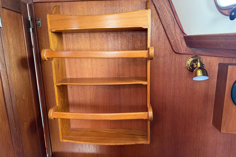 Acadia Yacht Photos Pics Wooden shelves inside a 1997 Tartan 3800 boat, featuring a brass wall light.