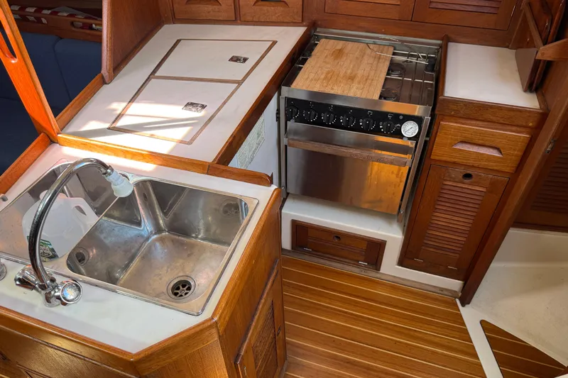 Acadia Yacht Photos Pics 1997 Tartan 3800 yacht kitchen with sink, stove, and wooden cabinetry.