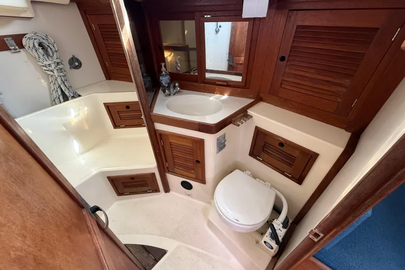 Acadia Yacht Photos Pics 1997 Tartan 3800 yacht bathroom with wooden cabinets, sink, and marine toilet.