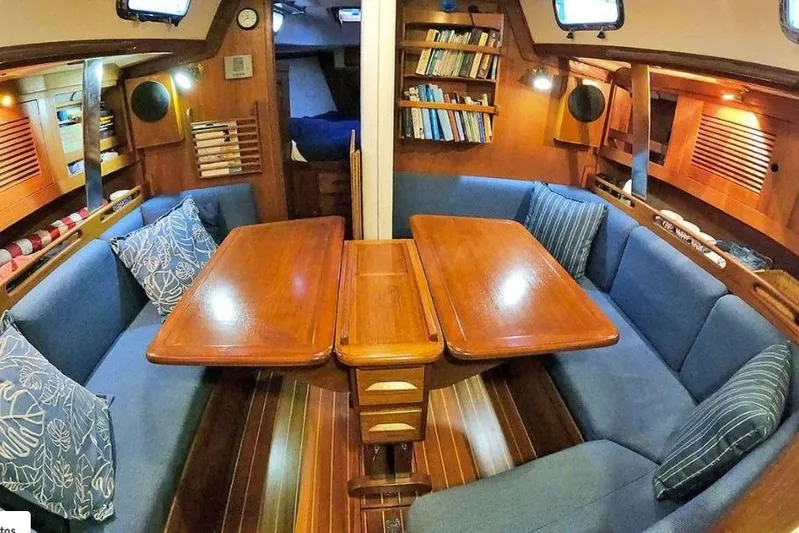 Acadia Yacht Photos Pics Interior of a 1997 Tartan 3800 sailboat with wooden table and blue seating.