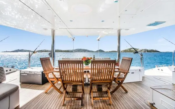 Euphoria Yacht Photos Pics Luxurious Sunreef 60 LOFT yacht deck with wooden dining set, overlooking serene ocean view.