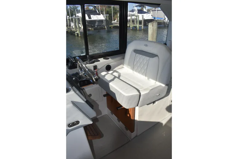  Yacht Photos Pics 2024 Regal 36 XO helm seat with steering wheel, docked by the water.