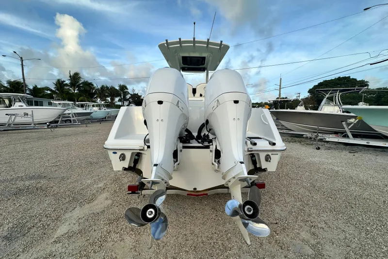  Yacht Photos Pics 2021 Edgewater 262CC boat with dual outboard motors, parked on gravel lot.