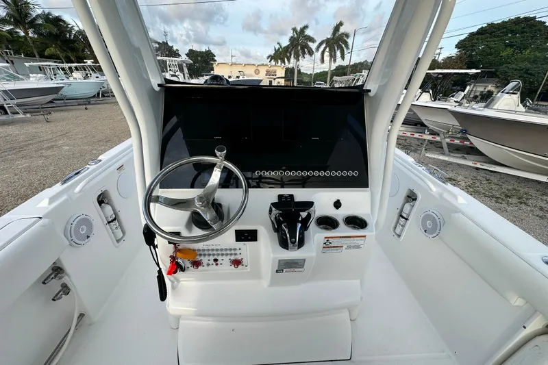  Yacht Photos Pics 2021 Edgewater 262CC boat console with steering wheel and controls, docked outdoors.