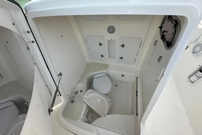  Yacht Photos Pics 2021 Edgewater 262CC boat interior with compact marine toilet and storage compartments.