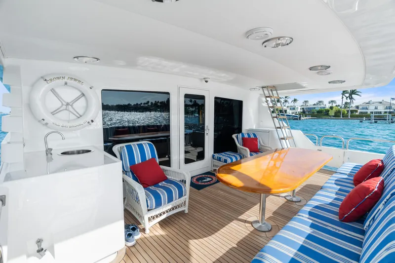 Crown Jewel Yacht Photos Pics Luxurious 1996 Broward 96 Raised Pilothouse MY yacht deck with striped seating and ocean view.