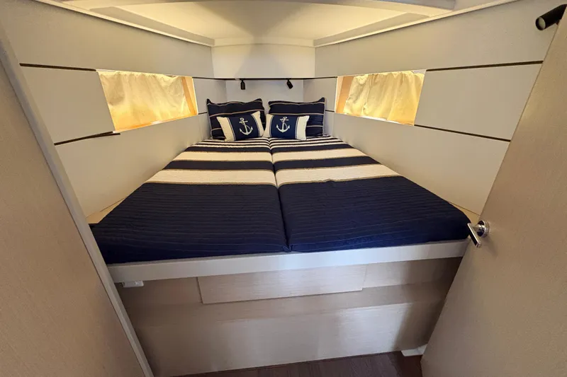  Yacht Photos Pics Cozy cabin interior of 2021 Beneteau Oceanis 38.1 with nautical-themed bedding.
