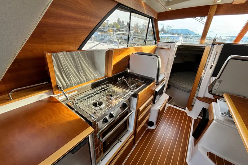  Yacht Photos Pics 2022 Cutwater C-32 CB interior with modern kitchen, featuring stove and wooden cabinetry.