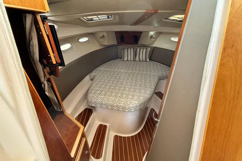  Yacht Photos Pics 2022 Cutwater C-32 CB cabin interior with bed, wood accents, and portholes.