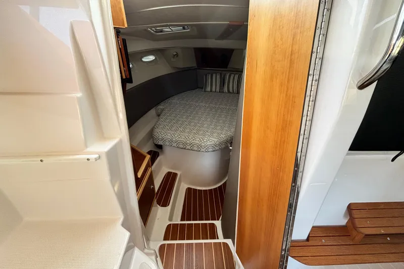  Yacht Photos Pics Interior cabin of 2022 Cutwater C-32 CB boat with wood accents and cozy bed.