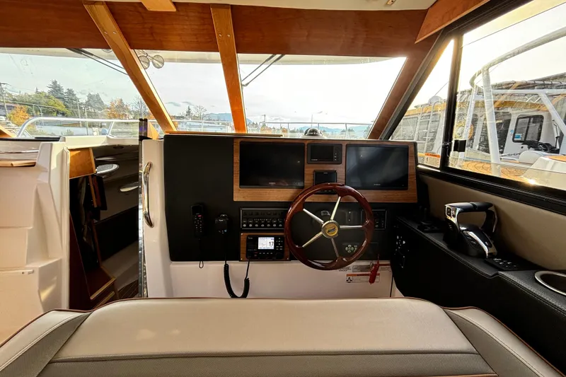  Yacht Photos Pics 2022 Cutwater C-32 CB helm with dual screens, wooden accents, and modern controls.