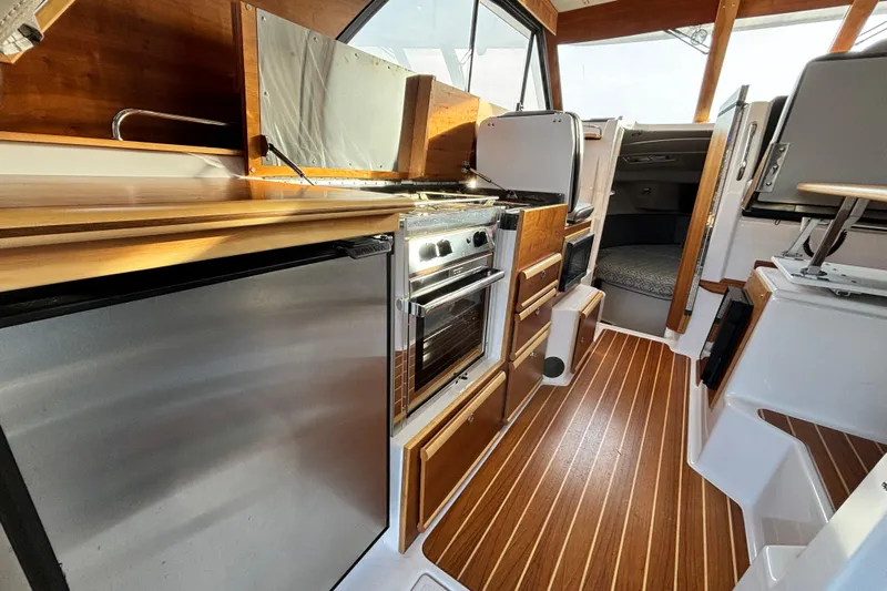  Yacht Photos Pics 2022 Cutwater C-32 CB boat interior with modern kitchen, wood accents, and stainless steel appliances.
