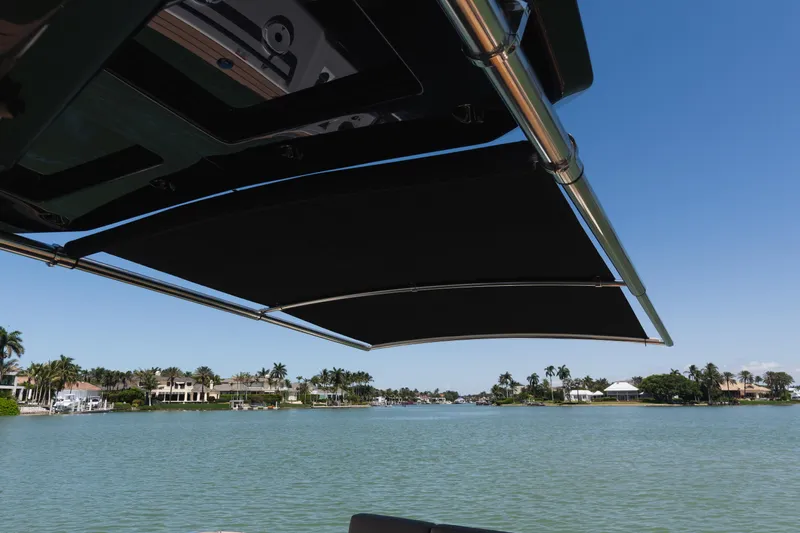  Yacht Photos Pics 2025 Pardo Yachts P38 with sunshade, overlooking serene waterfront and palm trees.