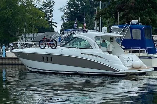  Yacht Photos Pics 2008 Cruisers Yachts 390 Sports Coupe on a calm waterway, docked near other boats.