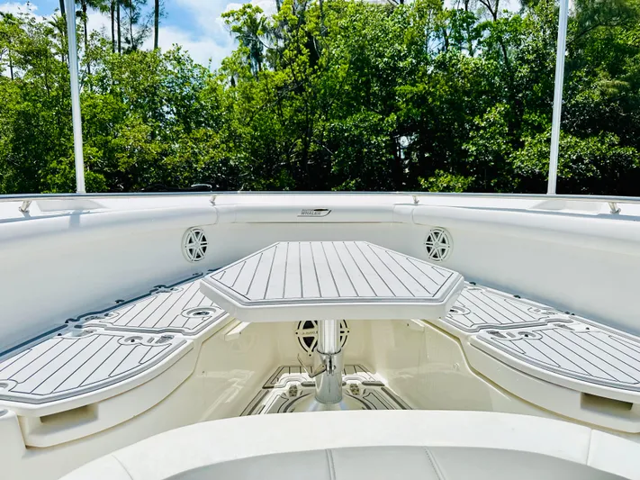  Yacht Photos Pics 2016 Boston Whaler 350 Outrage boat interior with seating and table, surrounded by greenery.