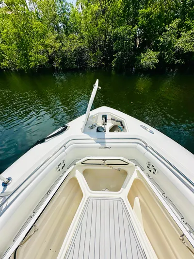  Yacht Photos Pics 2016 Boston Whaler 350 Outrage boat on calm water, surrounded by lush greenery.