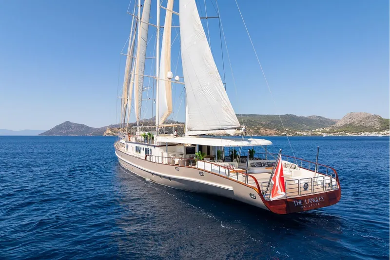 The Langley Yacht Photos Pics Aegean Yacht 3 Mast Schooner, 2009, sailing in clear blue waters near a scenic coastline.