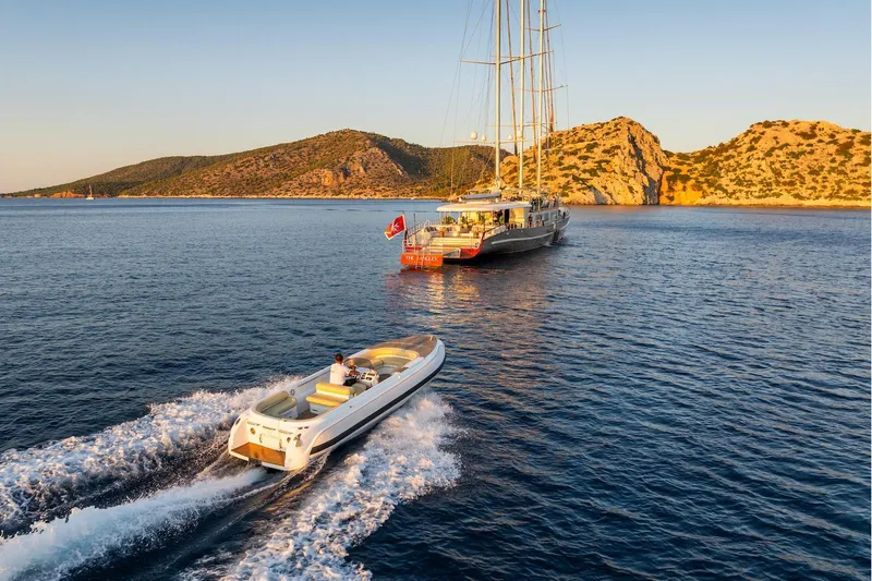 The Langley Yacht Photos Pics Aegean Yacht 3 Mast Schooner, 2009, anchored near scenic coastline with a speedboat approaching.