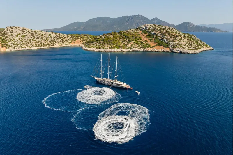 The Langley Yacht Photos Pics Aegean Yacht 3 Mast Schooner (2009) sailing near scenic islands with swirling water patterns.