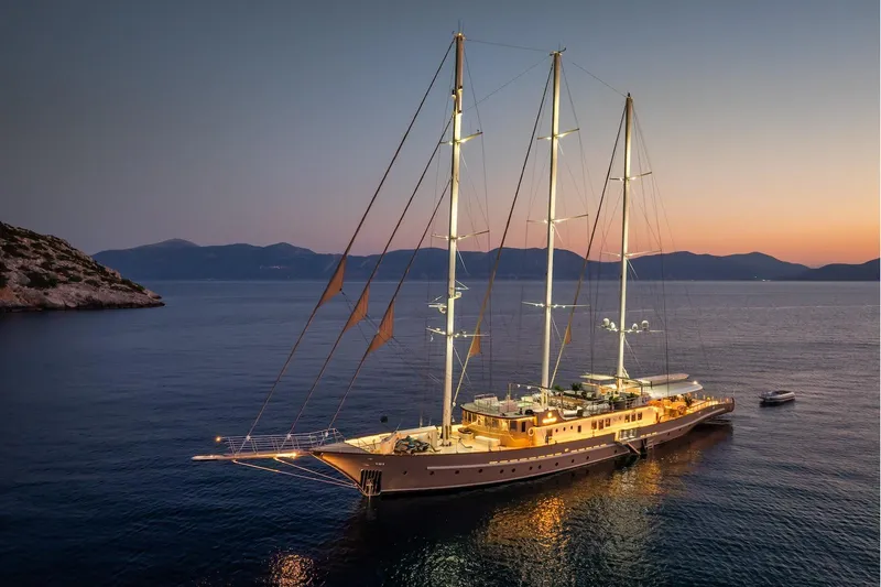 The Langley Yacht Photos Pics Luxurious 2009 Aegean Yacht 3 Mast Schooner illuminated at sunset on tranquil waters.