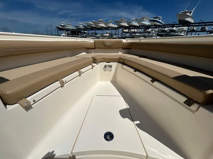  Yacht Photos Pics 2018 Scout 275 LXF boat interior with tan seating and storage, docked under blue sky.