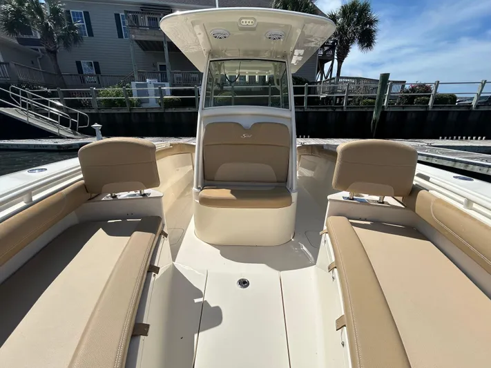  Yacht Photos Pics 2018 Scout 275 LXF boat interior with beige seating and console, docked near waterfront homes.