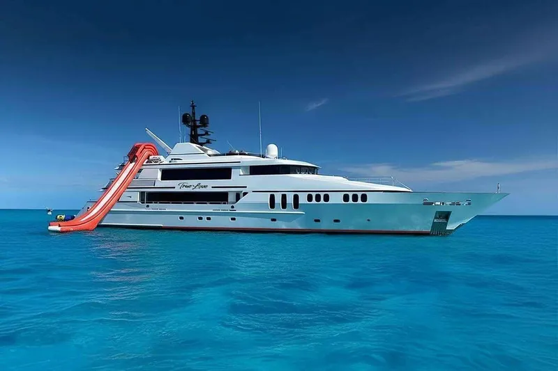 True Love Yacht Photos Pics Luxurious 2003 Trinity Yachts motoryacht with waterslide, anchored in clear blue ocean.