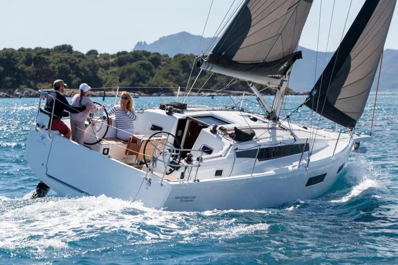 C'est Chic Yacht Photos Pics Manufacturer Provided Image: 2025 Jeanneau Sun Odyssey 350 sailing on clear blue waters with lush green coastline.