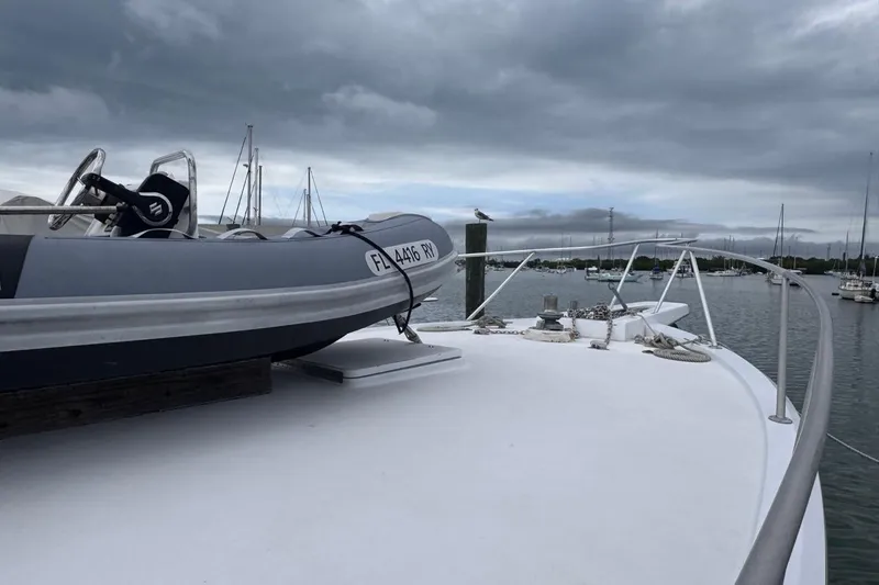  Yacht Photos Pics 1979 Hatteras 53 Motor Yacht deck with dinghy, moored in a marina under cloudy skies.
