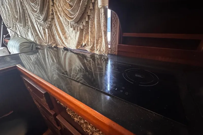  Yacht Photos Pics Luxurious kitchen interior of 1979 Hatteras 53 Motor Yacht with elegant drapery and modern cooktop.