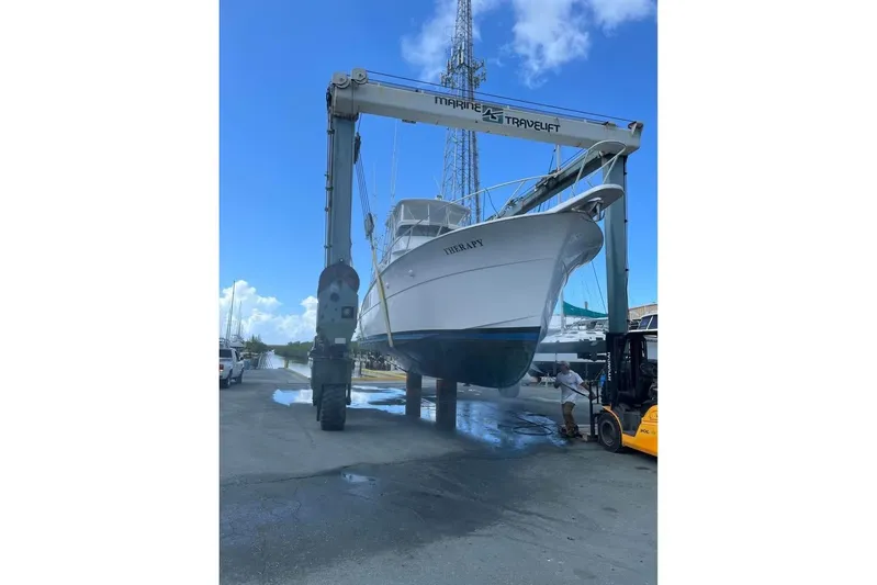  Yacht Photos Pics 1979 Hatteras Sportfish 53' yacht lifted by marine travelift under blue sky.