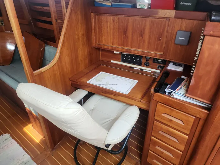 Sensation Yacht Photos Pics Navigation station in 1998 Tartan 4100 sailboat with wooden cabinetry and white chair.