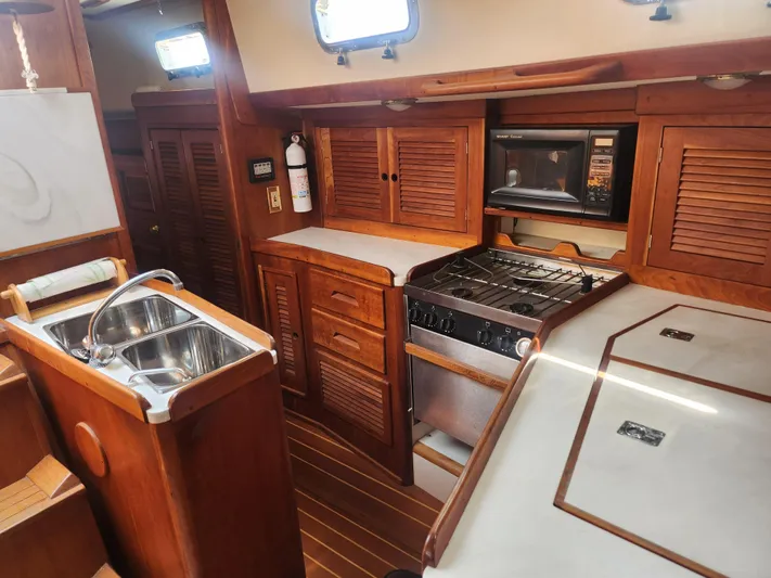 Sensation Yacht Photos Pics 1998 Tartan 4100 yacht kitchen with wooden cabinetry, stove, and sink.