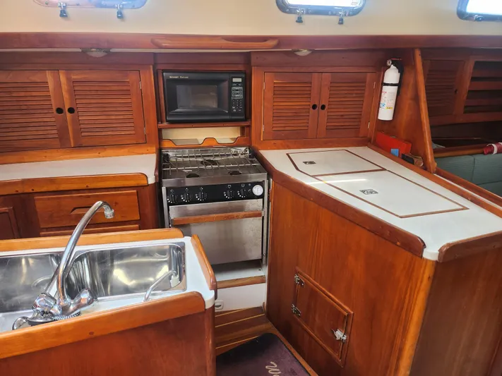 Sensation Yacht Photos Pics 1998 Tartan 4100 yacht kitchen with wooden cabinets, stove, microwave, and sink.