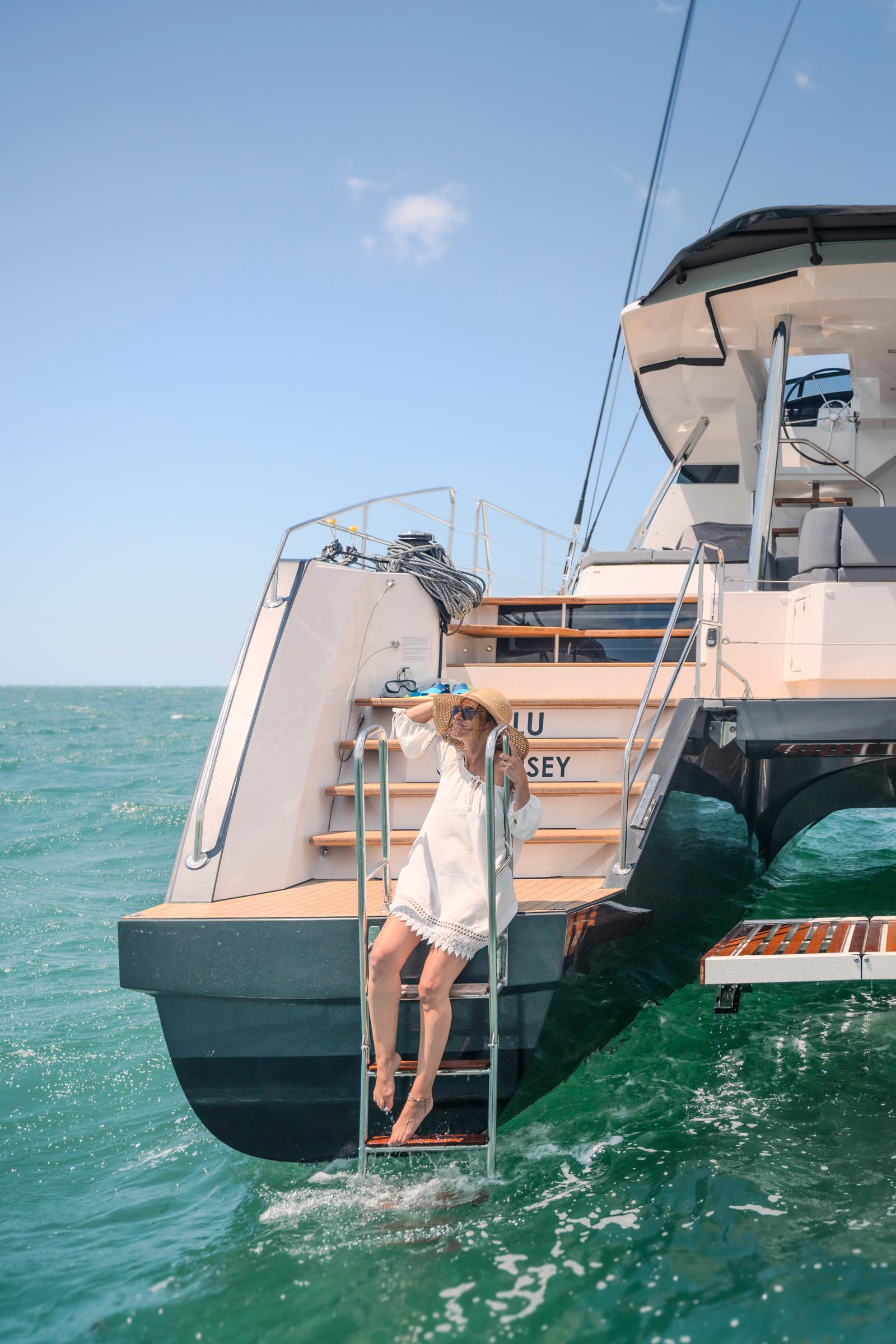 Woman relaxing on a 2025 Privilege Signature 650 yacht ladder, ocean backdrop.