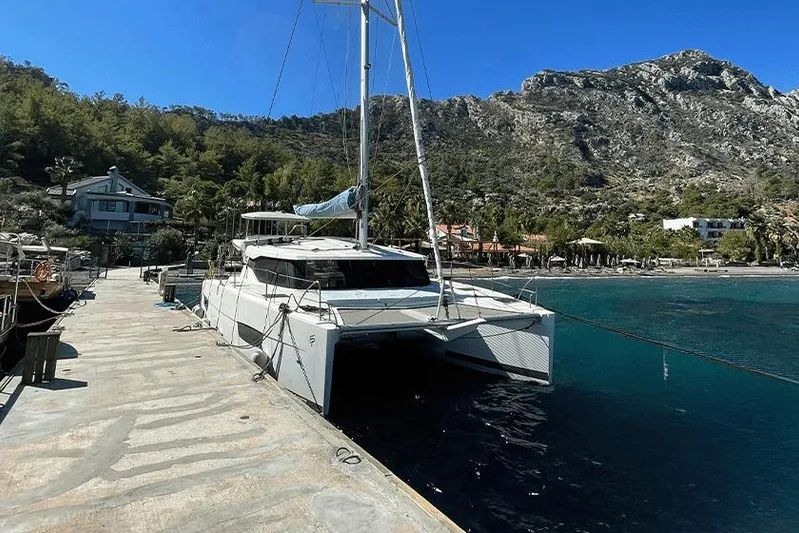 Yacht Photos Pics 2018 Fountaine Pajot Lucia 40 catamaran docked by scenic coastal landscape.
