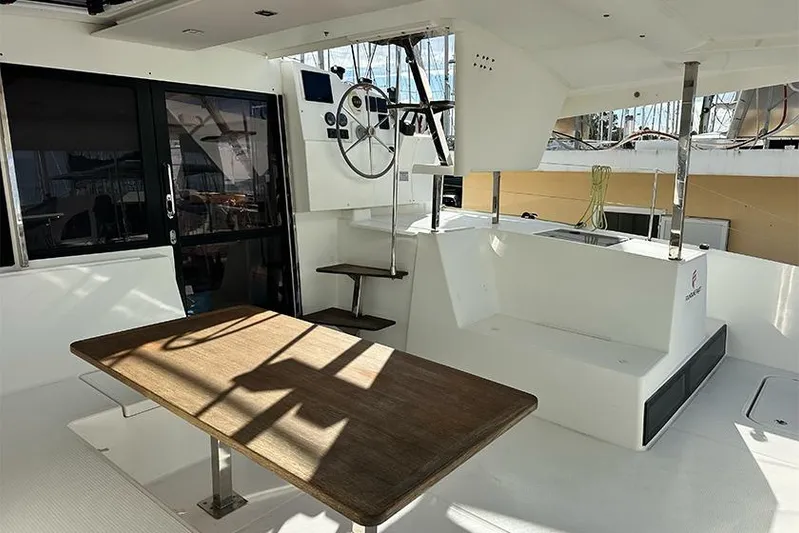  Yacht Photos Pics 2018 Fountaine Pajot Lucia 40 catamaran cockpit with helm, seating, and wooden table.