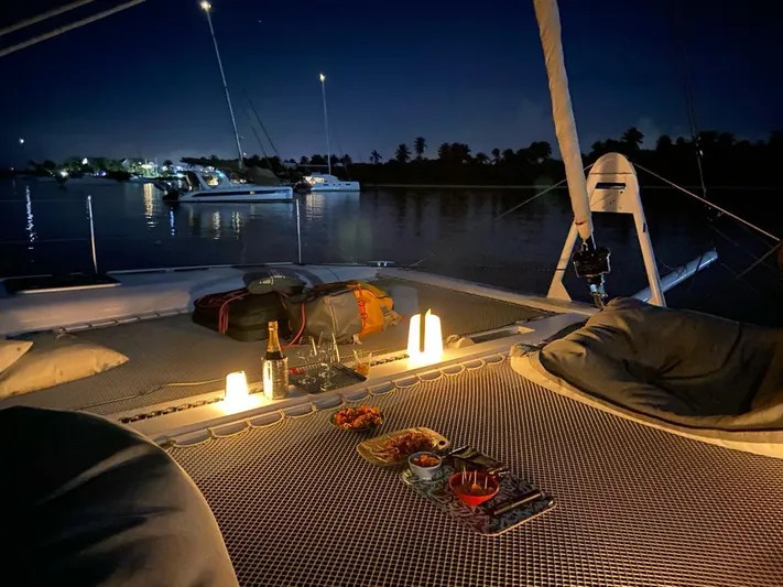 Peems Yacht Photos Pics 2022 Outremer 45 catamaran at night, featuring cozy deck setup with candles and snacks.