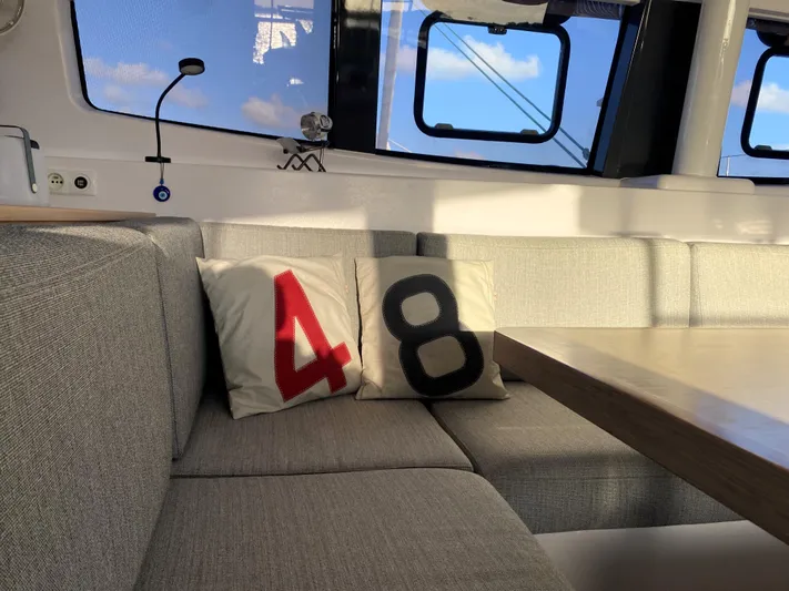 Peems Yacht Photos Pics Interior of 2022 Outremer 45 catamaran with numbered cushions on a gray sofa.