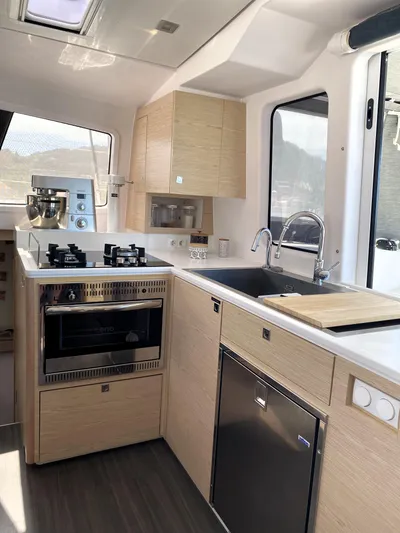 Peems Yacht Photos Pics Modern kitchen interior of 2022 Outremer 45 yacht with stove, sink, and cabinetry.