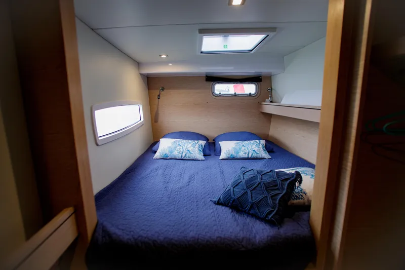 Peems Yacht Photos Pics Cozy bedroom interior of 2022 Outremer 45 yacht with blue bedding and natural light.