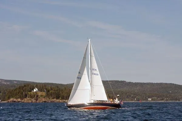 Courage Yacht Photos Pics 1980 Hinckley 43 sailboat cruising on a scenic lake with forested hills in the background.