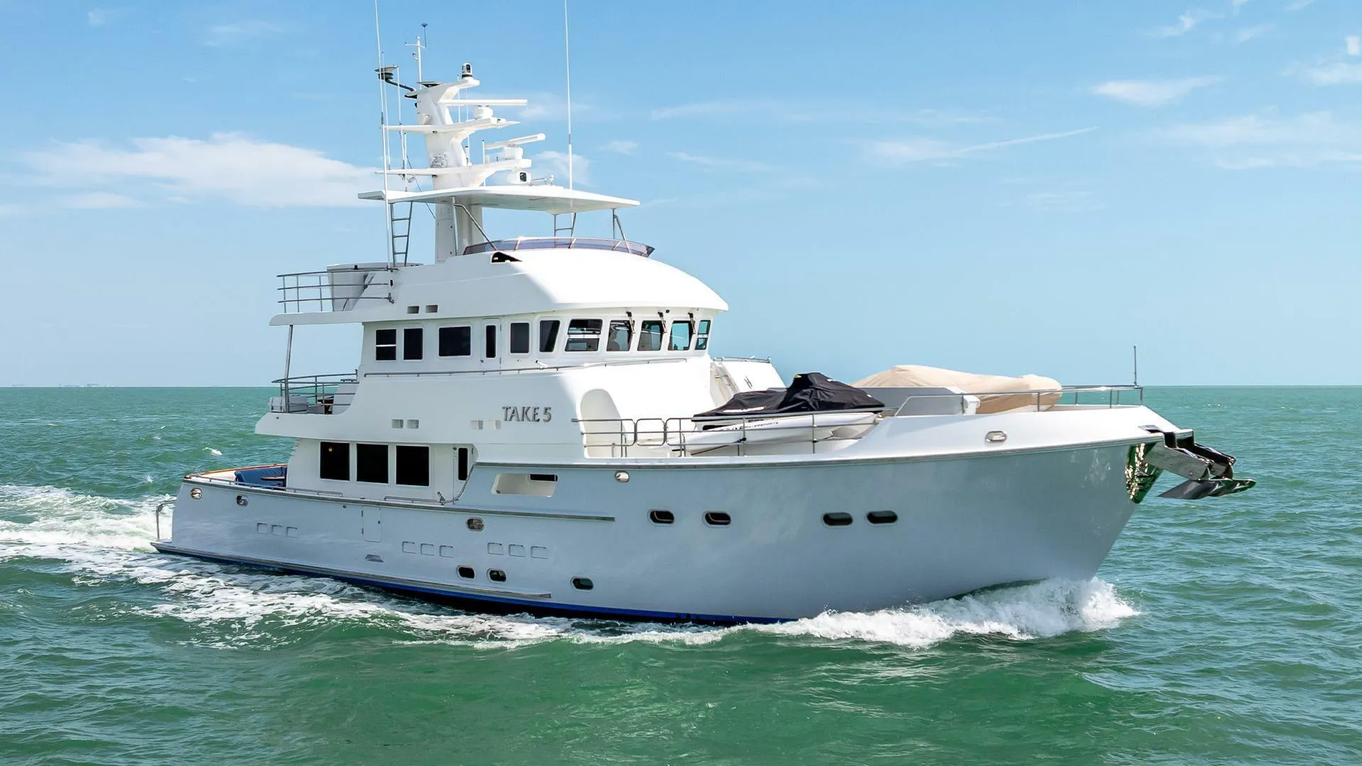 Nordhavn 76 yacht cruising on open sea, 2009 model, under clear blue sky.
