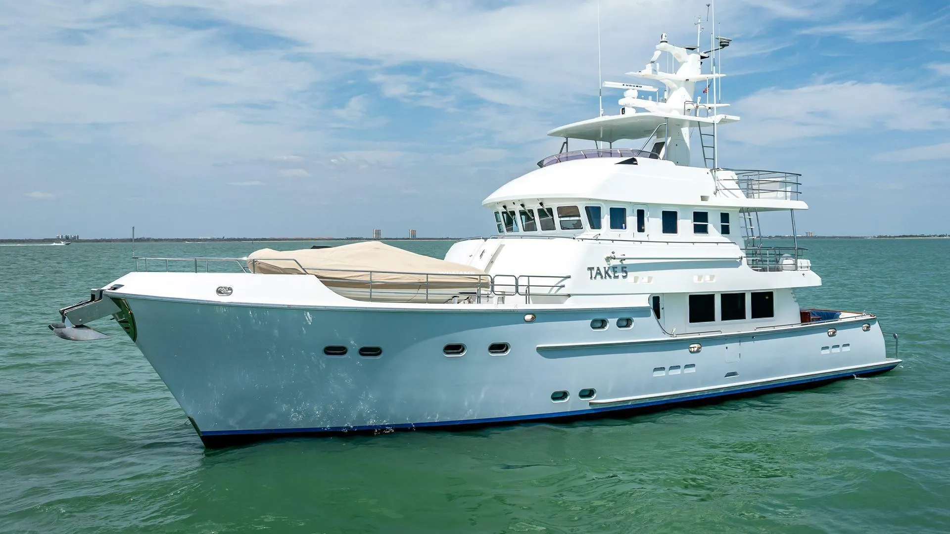 2009 Nordhavn 76 yacht on calm sea under blue sky.